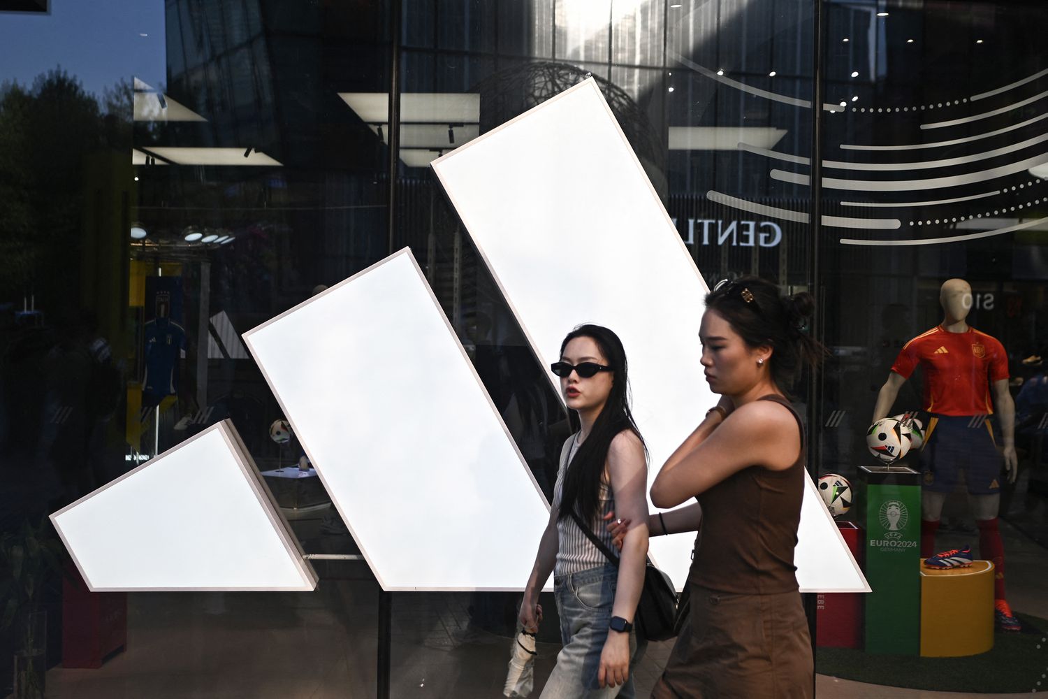 People walk past an Adidas store at a mall in Beijing on June 16, 2024. 