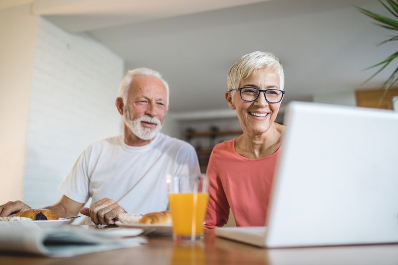 Retired senior couple looking at laptop together and smiling
