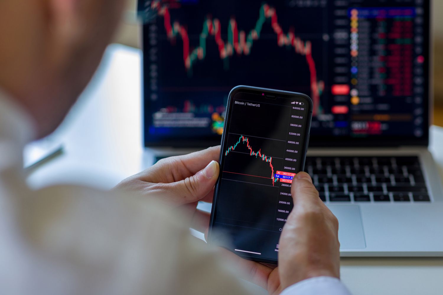 A stock investor analyzing trends in securities prices with their laptop and smartphone.