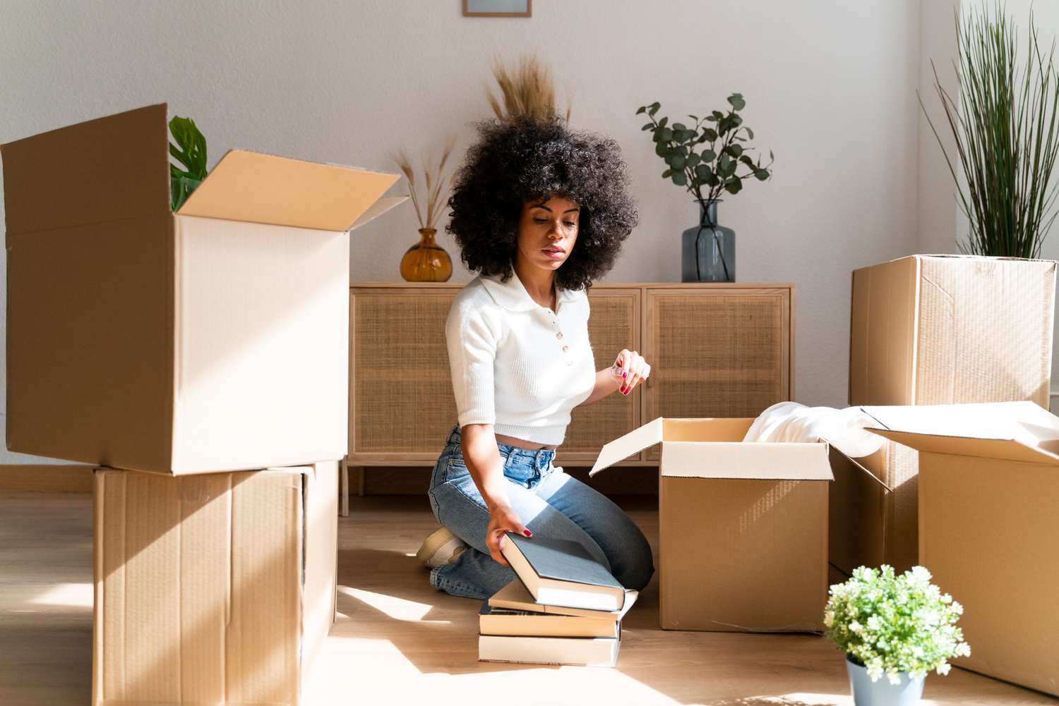 A woman unpacks boxes of books.