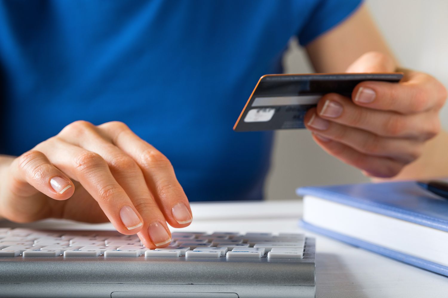 A Woman Is Holding A Credit Card, Typing on A Laptop Keyboard.