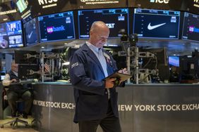 A trader looking down at a tablet he is holding and walking on the floor of the nYSE