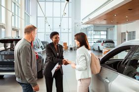 Couple picking up their new car at the dealership