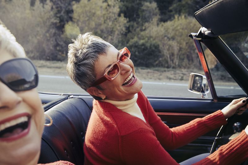 Two elderly women happily driving in a convertible