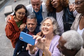 Senior friends taking a selfie or filming using mobile phone outdoors