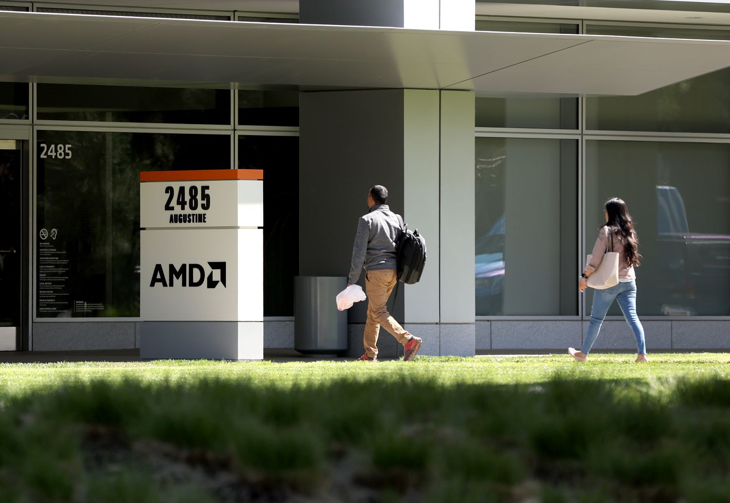Two people walking into an office with an AMD sign out front