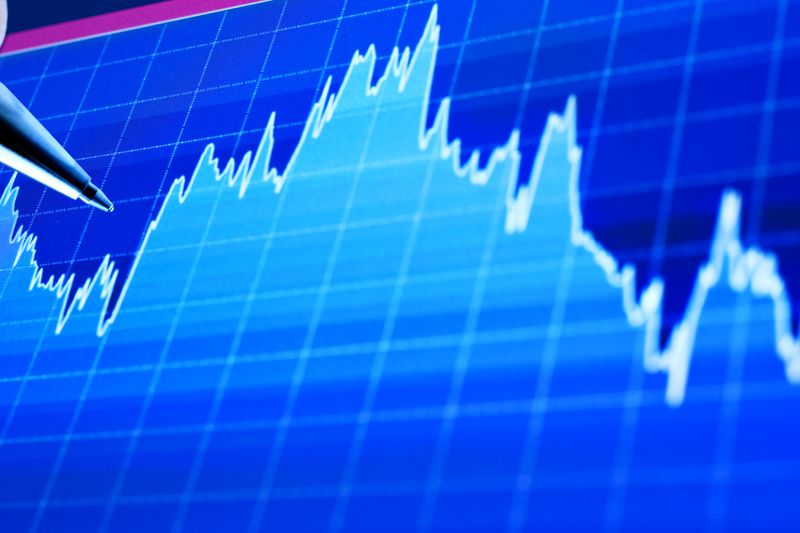 An analyst pointing with a pen on a stock chart display.