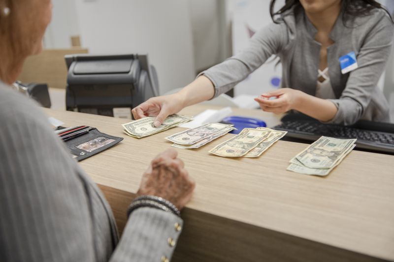 bank teller counts out cash for a customer