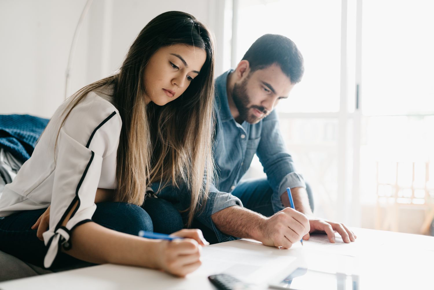 Young couple sitting on their sofa and working together on mortgage calculations