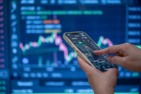 Hands on a smartphone showing a stock chart