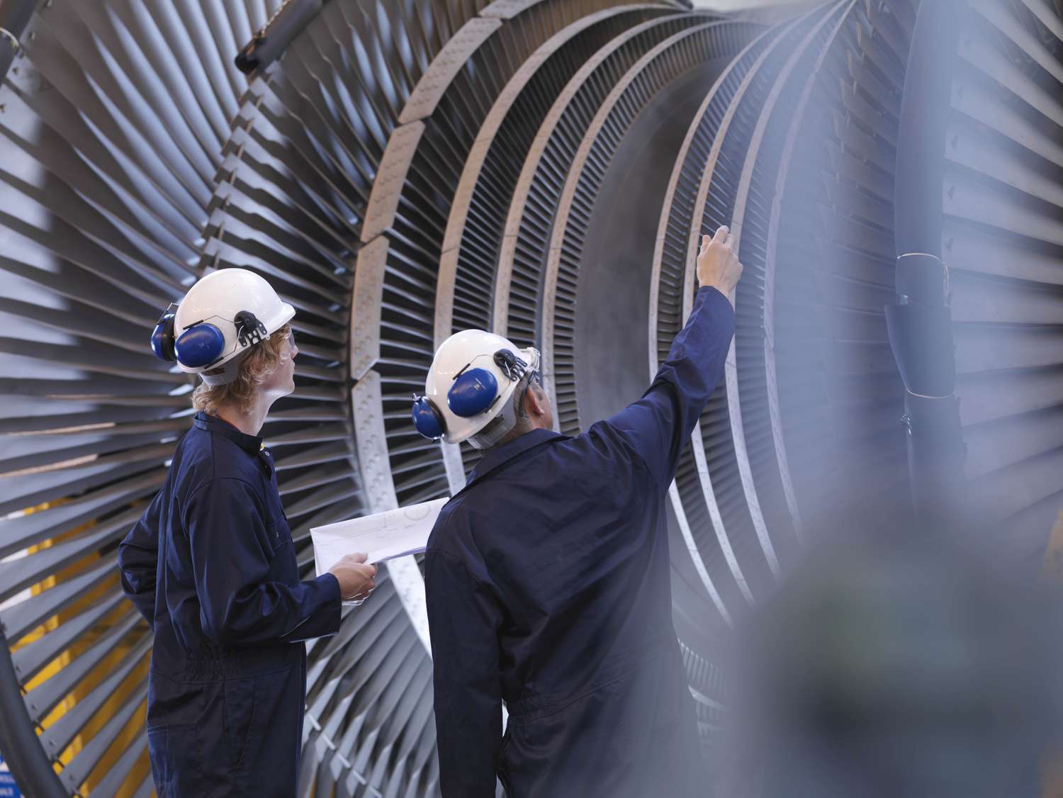 Engineers, representing OPEX, work on a turbine, representing CAPEX.