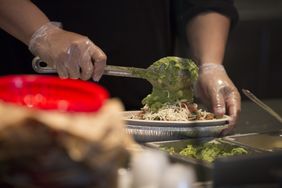 An employee places guacamole into a burrito bowl at a Chipotle Mexican Grill restaurant