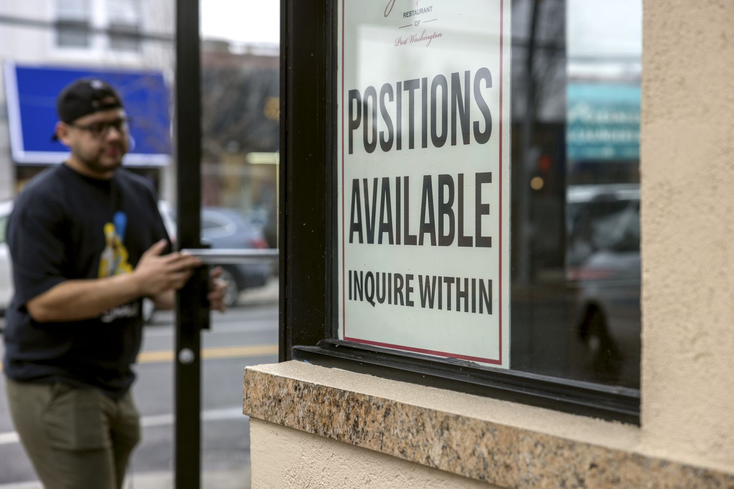 A Help Wanted sign seeking workers is on a window at Gino's Pizzeria & Restaurant on Main Street in Port Washington, New York, on January 5, 2022. 