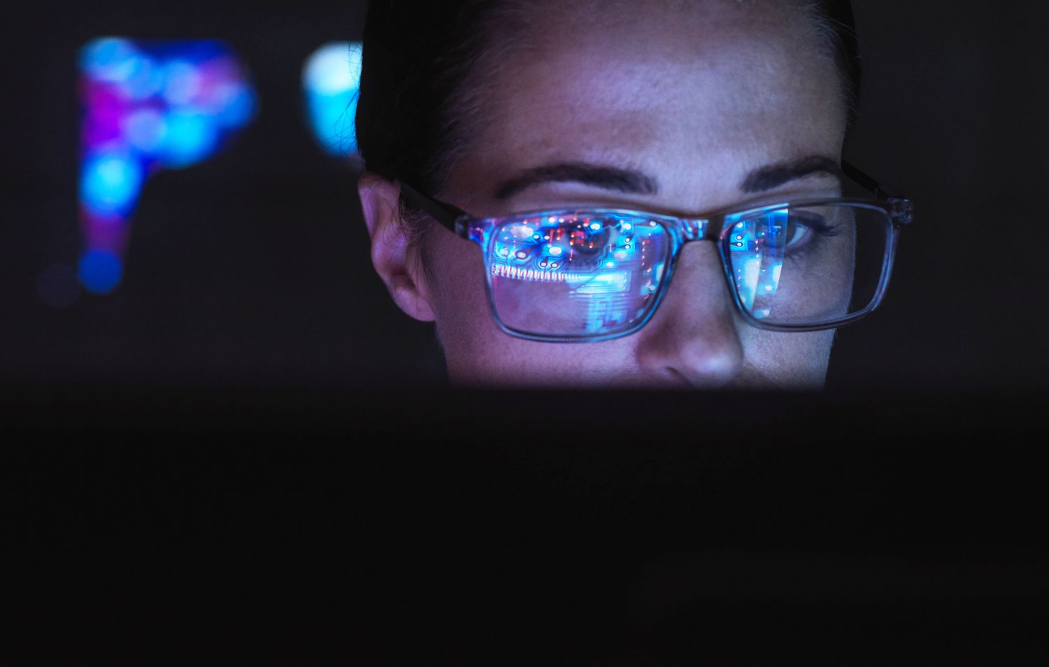 Engineer designing AI technology with screen reflection on eyeglasses