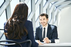 Smiling Businessman Looking at Businesswoman in Modern Office