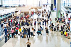 A stock image of travelers waiting in line at an airport. 