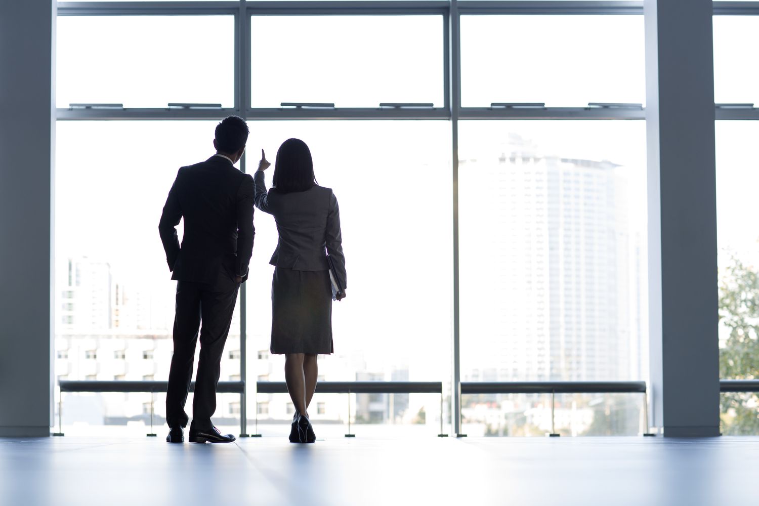 Rear view of business workers looking through high rise office building window