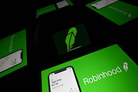 The Robinhood logo is seen in the center of four reflections of screens displaying the company's logo.