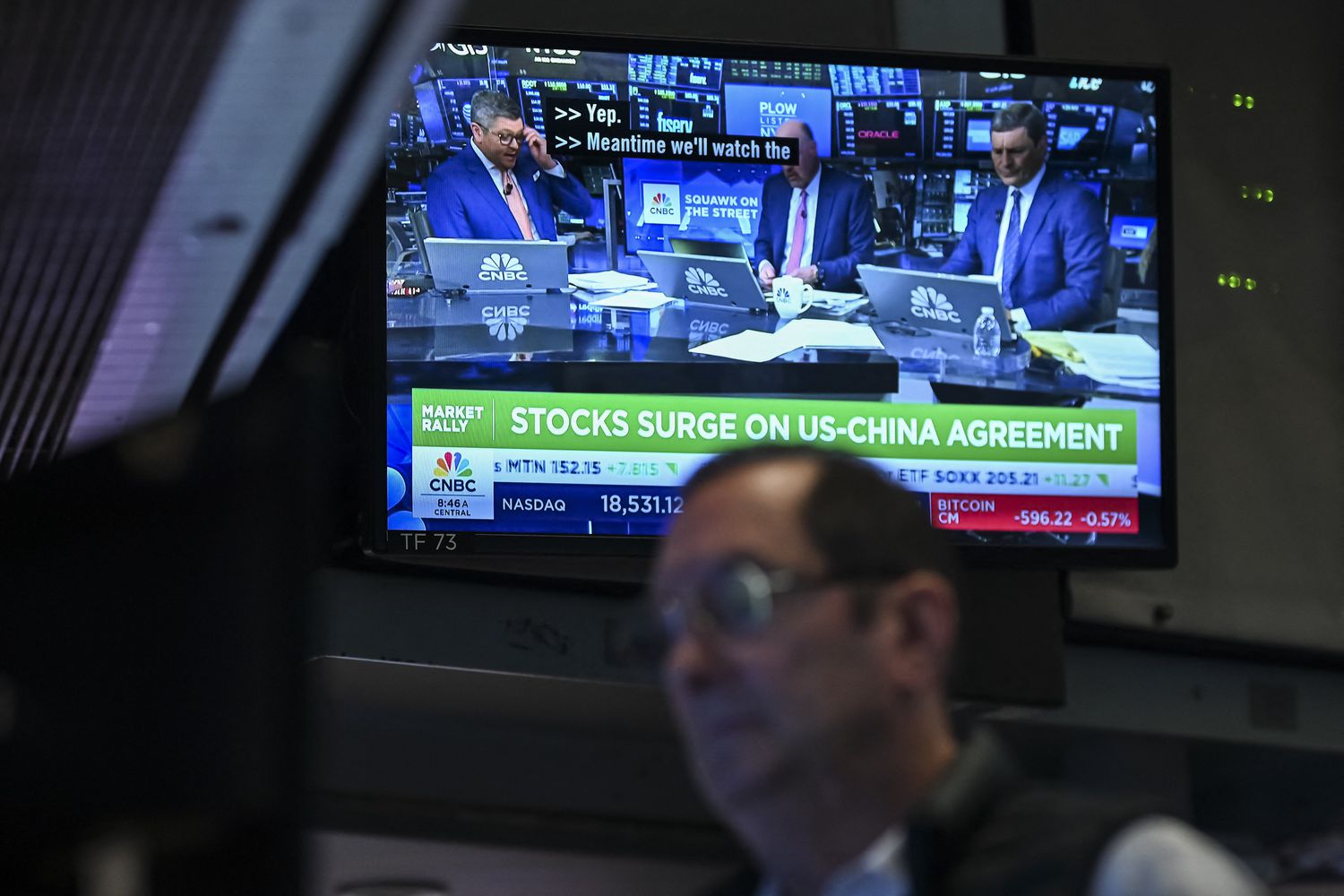 A trader works on the floor of the New York Stock Exchange in front of a screen showing stock market news