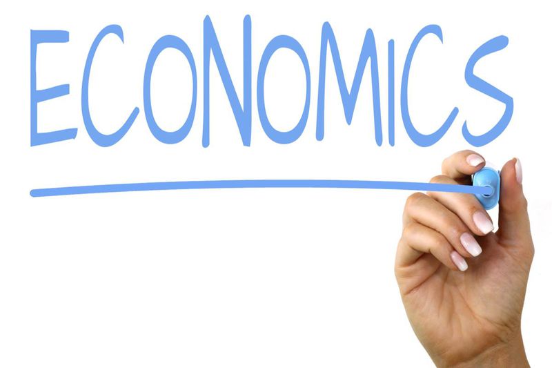 Person writing on whiteboard the word economics
