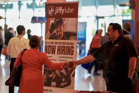 Job fair with a Jiffy Lube recruitment banner, two individuals interacting in front of it