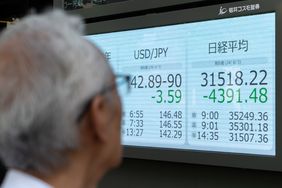 A pedestrian looks at a monitor displaying the Nikkei 225 Stock Average figure outside a securities firm.