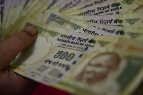 Finger on rupee notes spread fan like