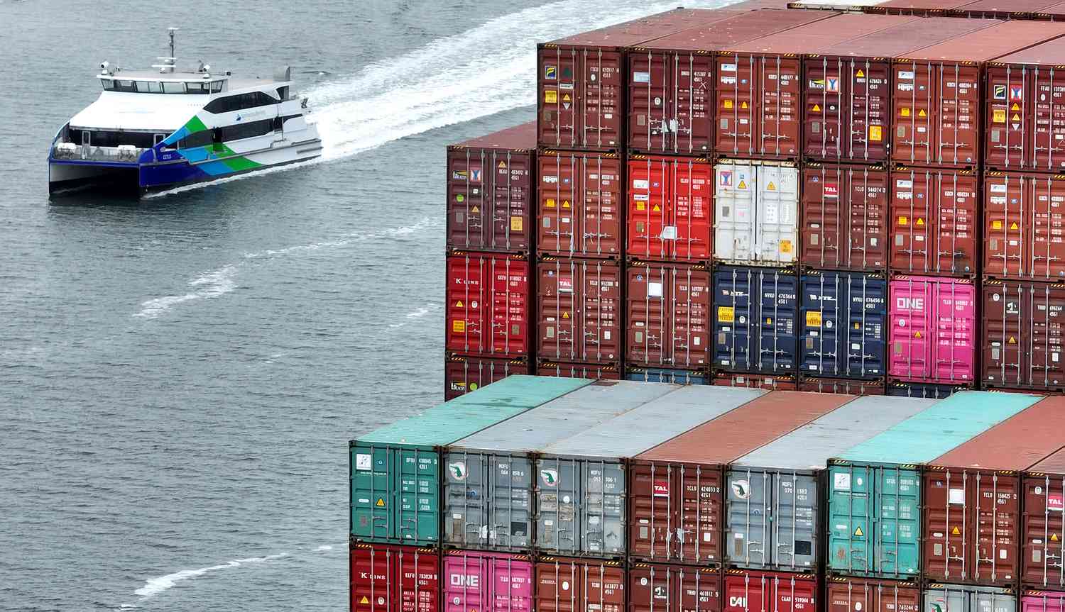 Shipping containers stacked on a ship as a smaller boat passes by