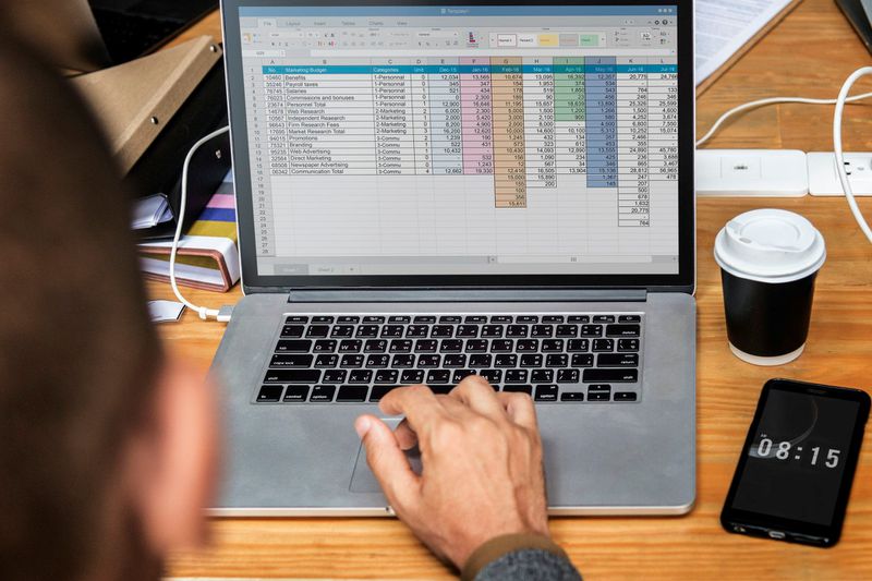 Person using excel on Mac laptop.