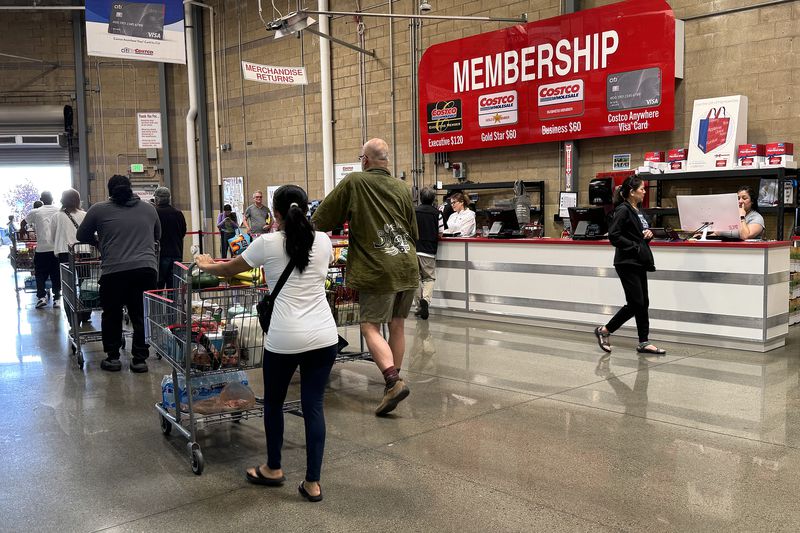 Several customers with shopping carts at Costco near the exit and membership desk. 