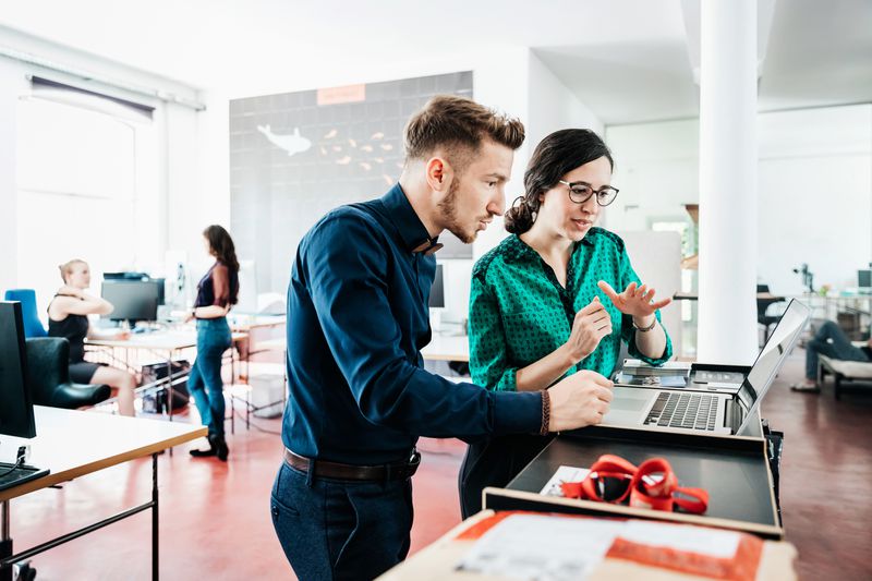 Two co-workers discussing business over a laptop.