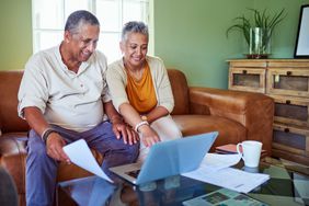 Older couple sitting on their sofa and looking at mortgage documents and online mortgage rates