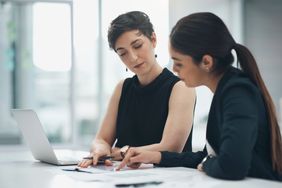 Two businesswomen review papers