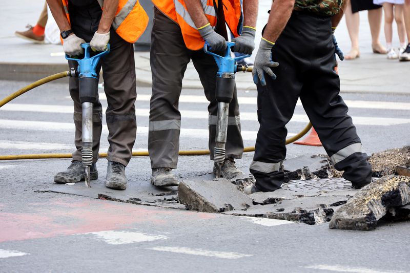 City workers use jackhammers to remove the road surface for an infrastructure-related repair of the storm sewer.