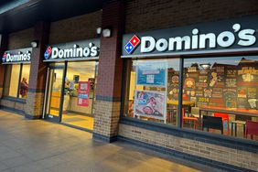 The Domino's Pizza logo is seen above the windows and doors of a restaurant.
