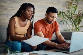 Young couple sitting on their sofa and looking a documents and a laptop