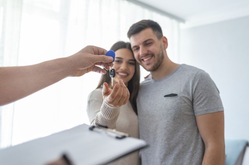 Hands of estate agent giving keys to renting couple