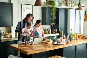 Husband and wife playing with their child while cooking in the kitchen and discussing to cancel their home equity loan.