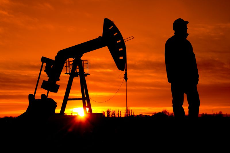 An oil field worker stands near a pump in Alberta, Canada.