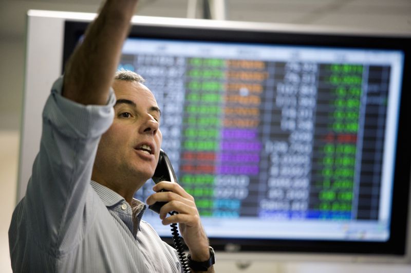 A stock trader on the floor of the stock exchange signaling a trade based on current stock prices.