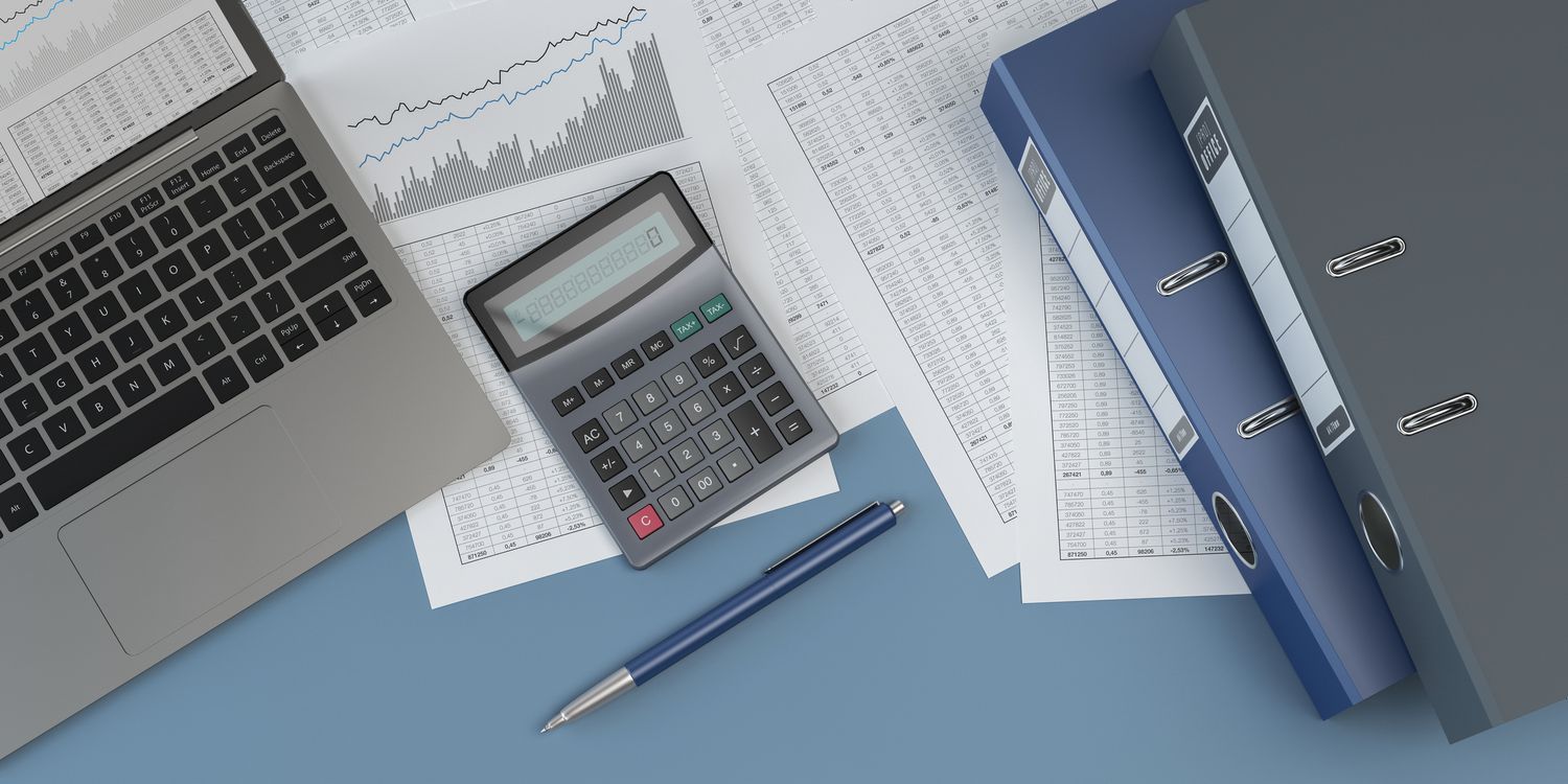 Documents, ring binders, a laptop, a pen and a calculator.
