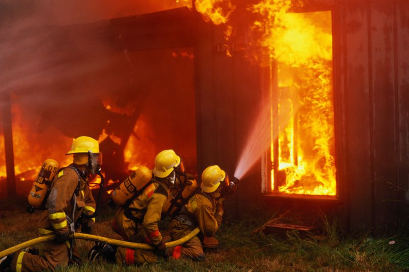 Firefighters with water hose controlling house fire