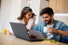 Happy couple in the kitchen at home reading a document informing a principal reduction on their mortgage.