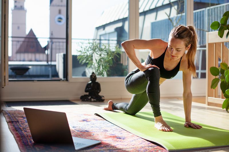 a woman doing yoga in front of a laptop