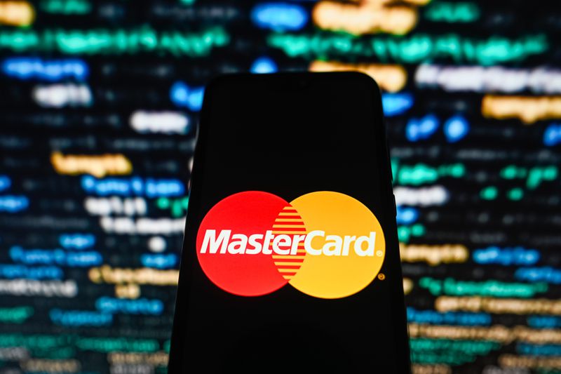 In this photo illustration, a Mastercard logo seen displayed on a smartphone with coding in the background