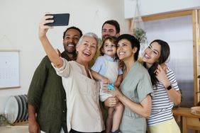 Cheerful family taking selfie with smart phone in kitchen