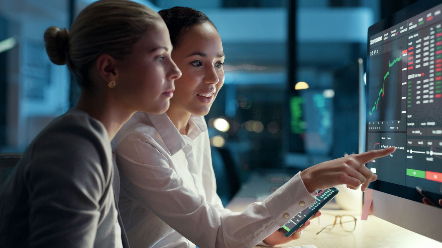 Professionals looking at financial data on a computer screen.