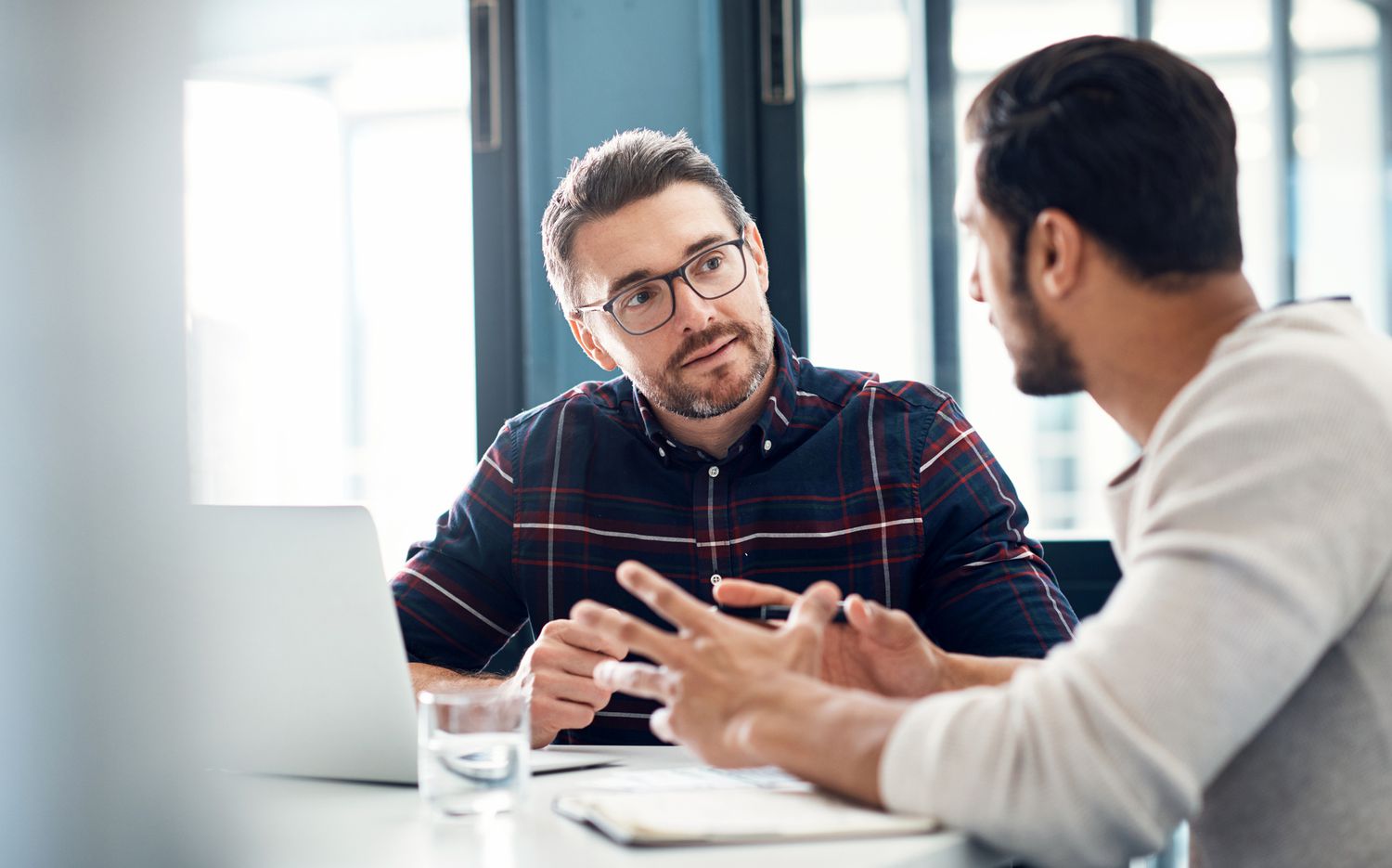 Two men have a discussion at a desk with documents about the best options to get $500 loan.
