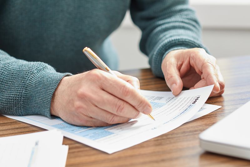 Person holding a pen and filling out a tax form