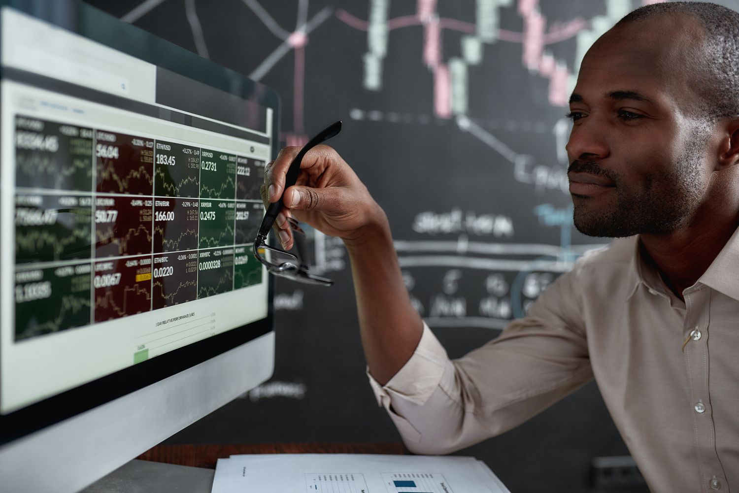 A serious options trader holds their glasses in their hand as the review data on a computer monitor and construct an options strap strategy trade.